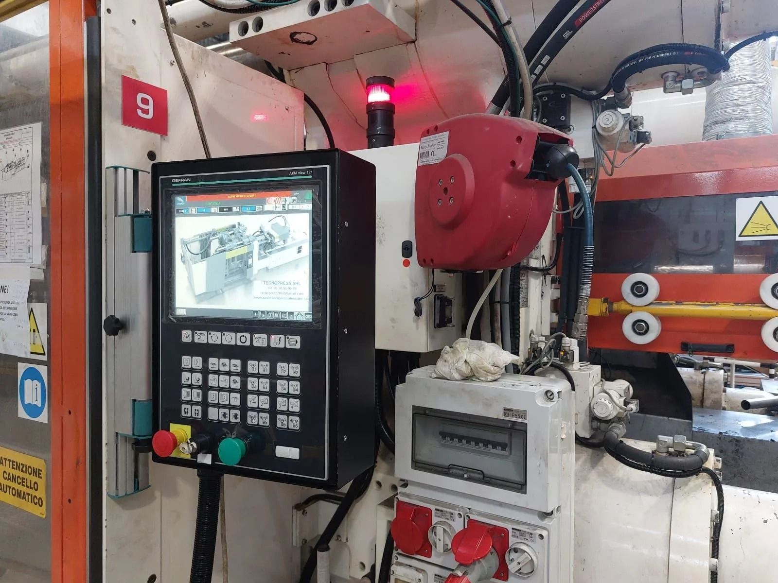 Pannello di controllo per macchina CNC e macchina industriale rossa all'interno di un'officina.