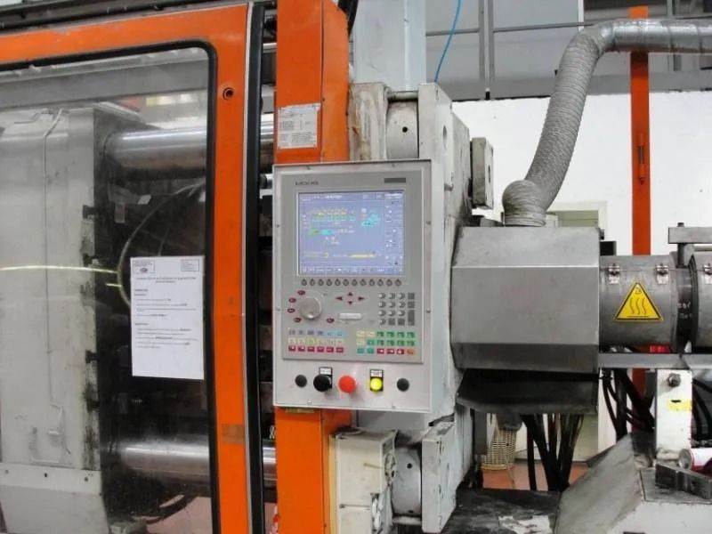 Pannello di controllo per macchinari industriali con pulsanti e display su una macchina di produzione arancione.