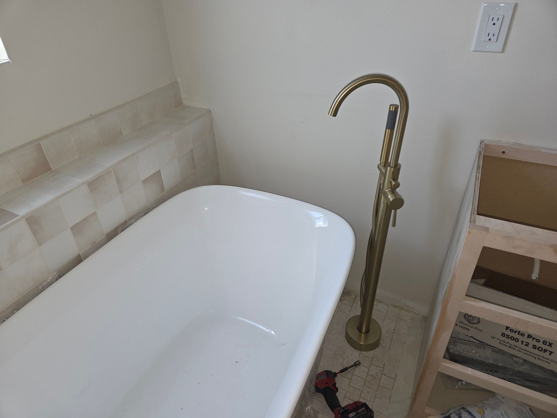White bathtub with brass faucet in a tiled bathroom corner