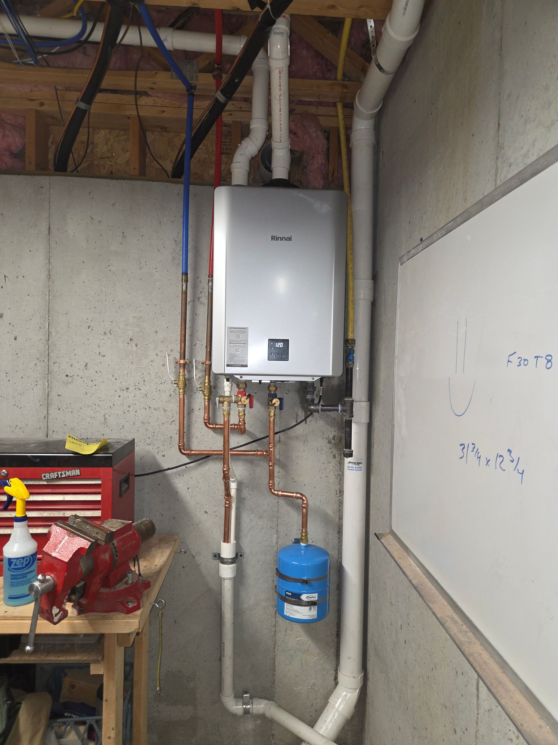 Utility room with a wall-mounted water heater, exposed pipes, and a blue expansion tank.