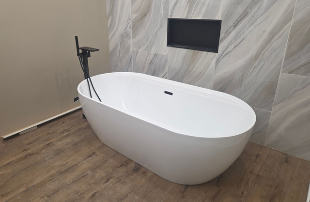 Modern bathroom with a freestanding white oval bathtub and black wall-mounted faucet
