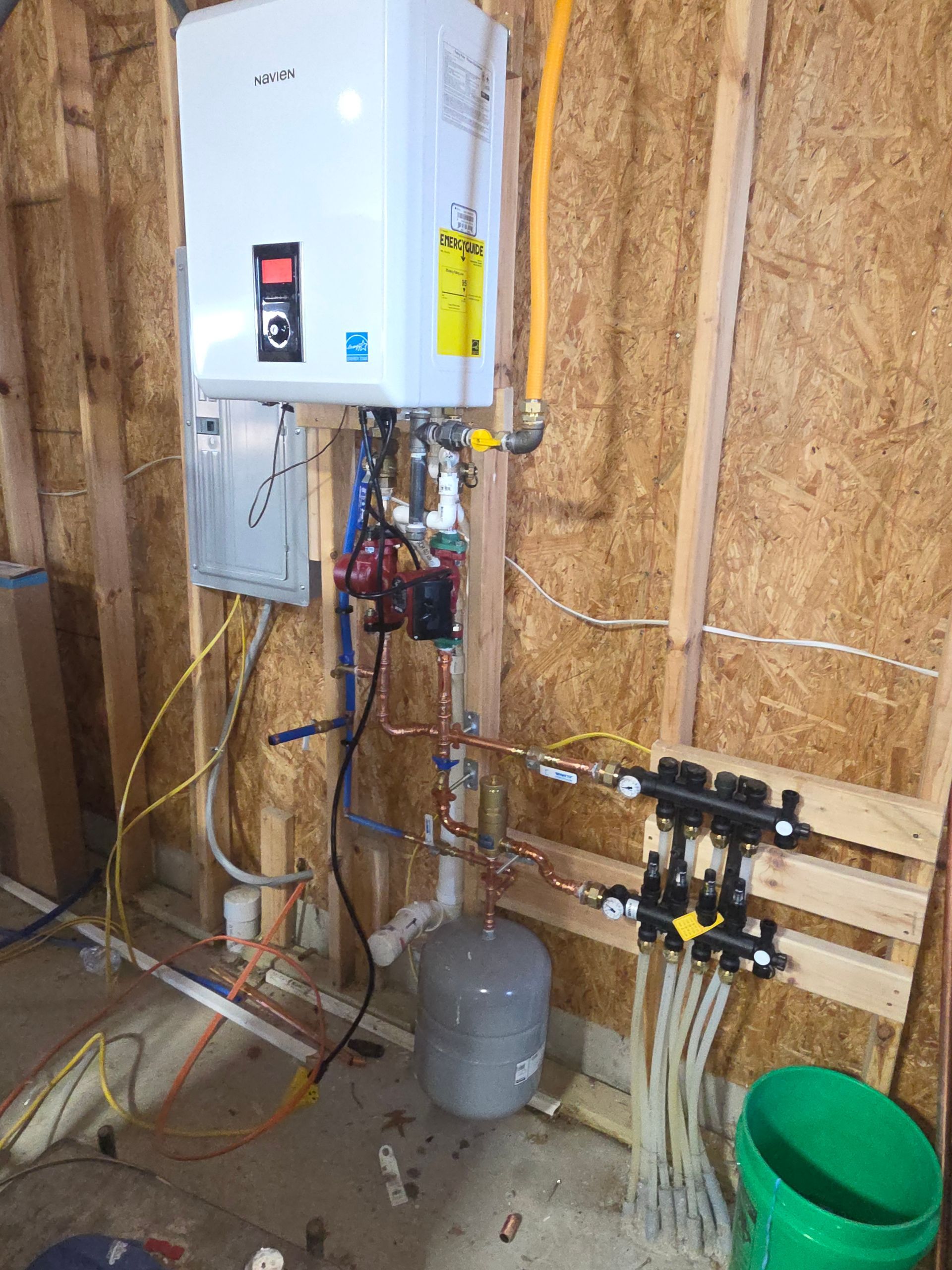 Water heater and plumbing in unfinished basement with exposed wood walls and utility equipment