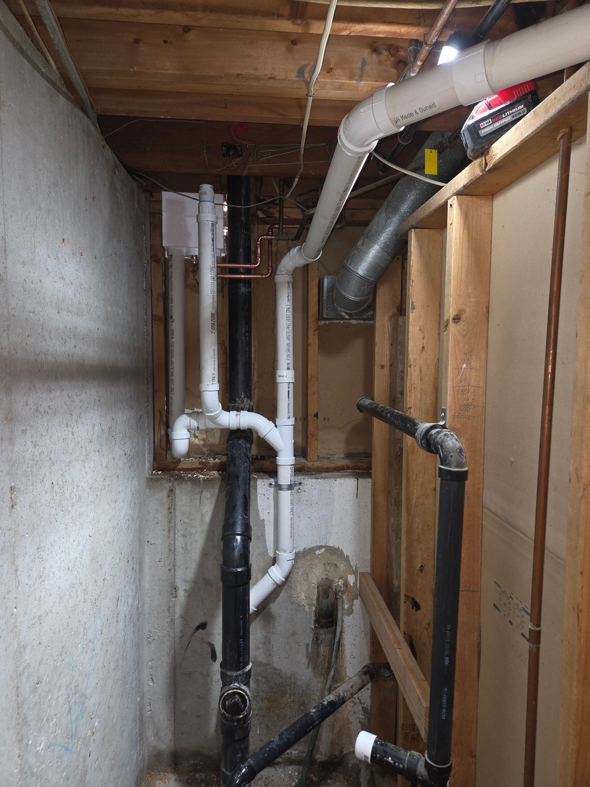 Narrow unfinished utility space with exposed pipes, ductwork, and wooden framing under the floor.