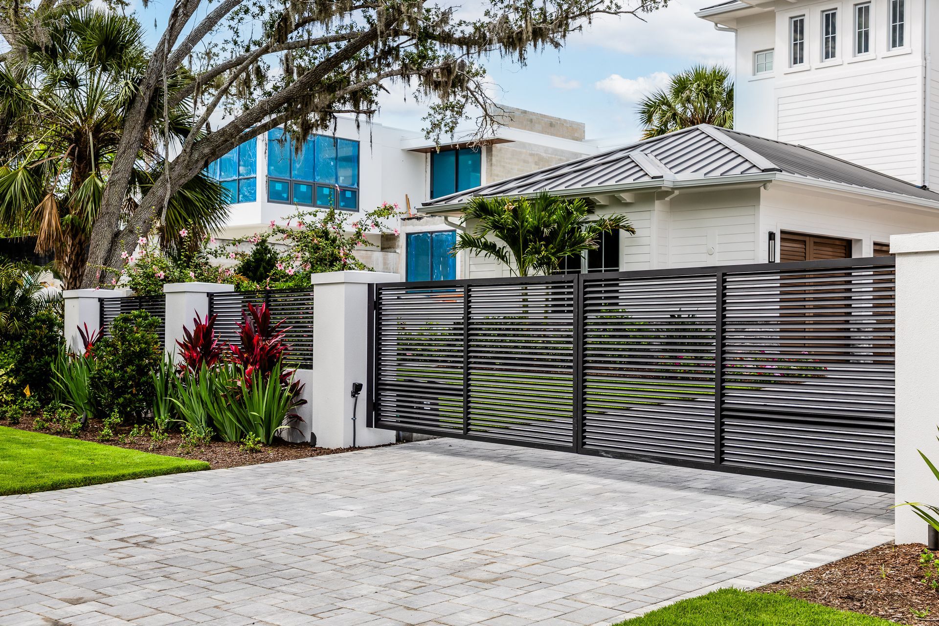 Modern house with white walls and black gate, front garden, and paved driveway
