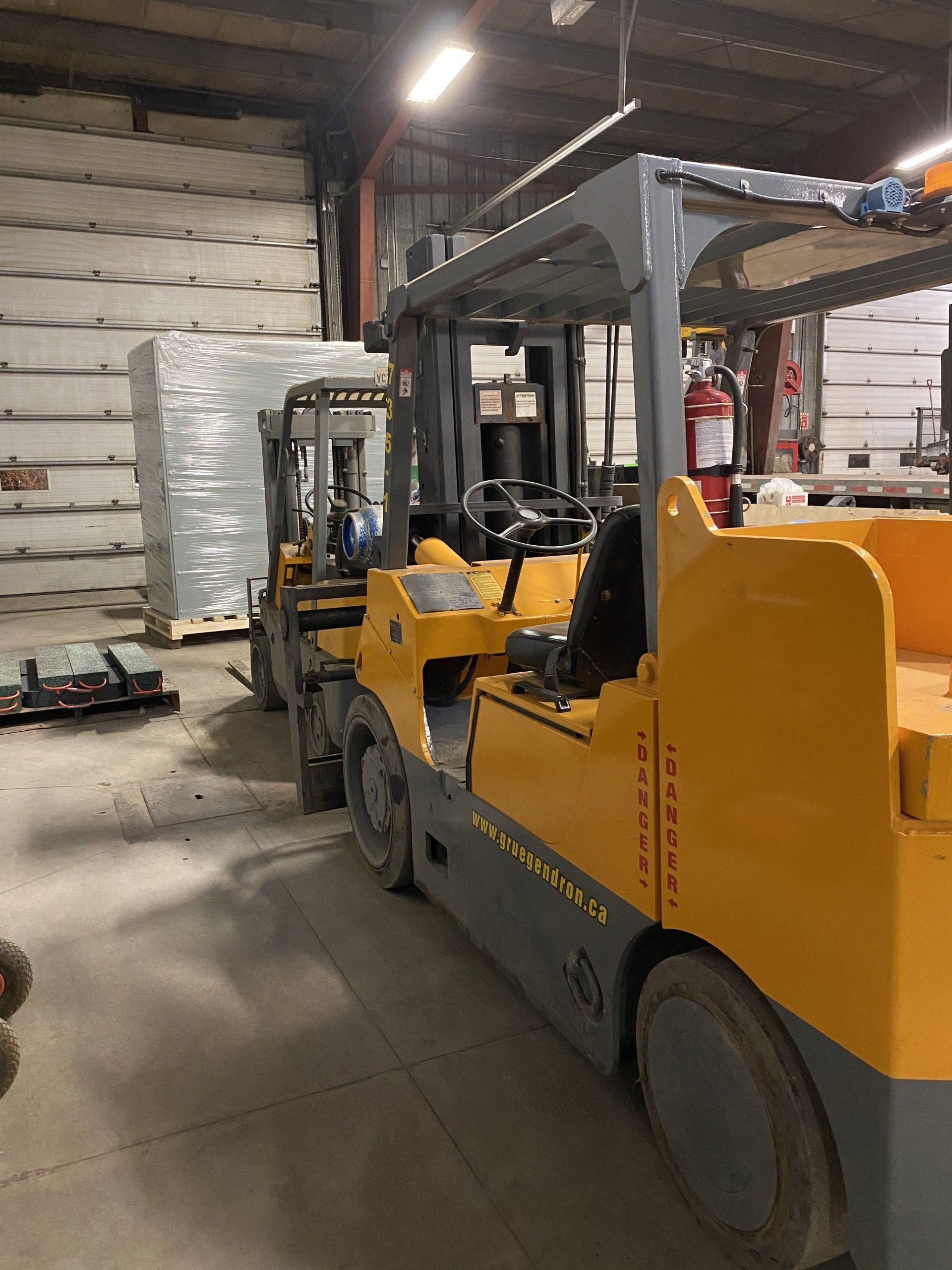 A row of forklifts are parked in a warehouse