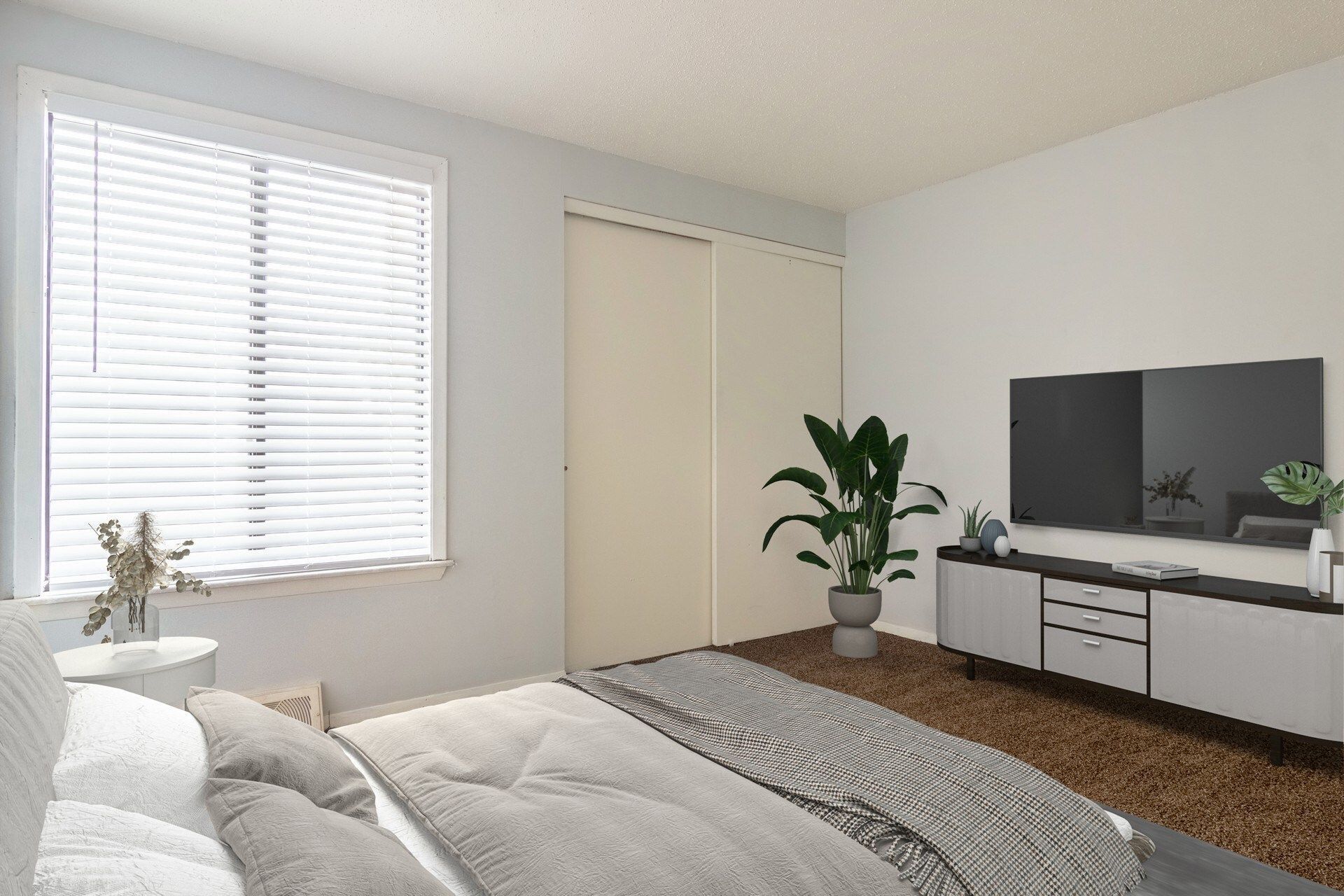Bedroom with closed blinds, a bed, TV, storage cabinet, and potted plant.