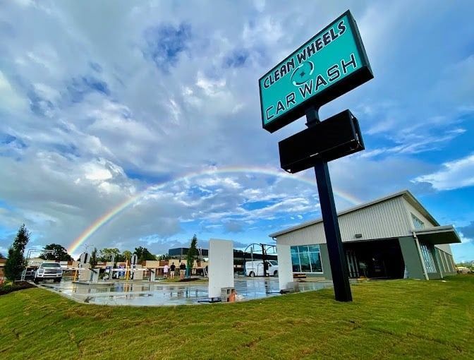 Car wash sign beside a wet parking lot under a cloudy blue sky