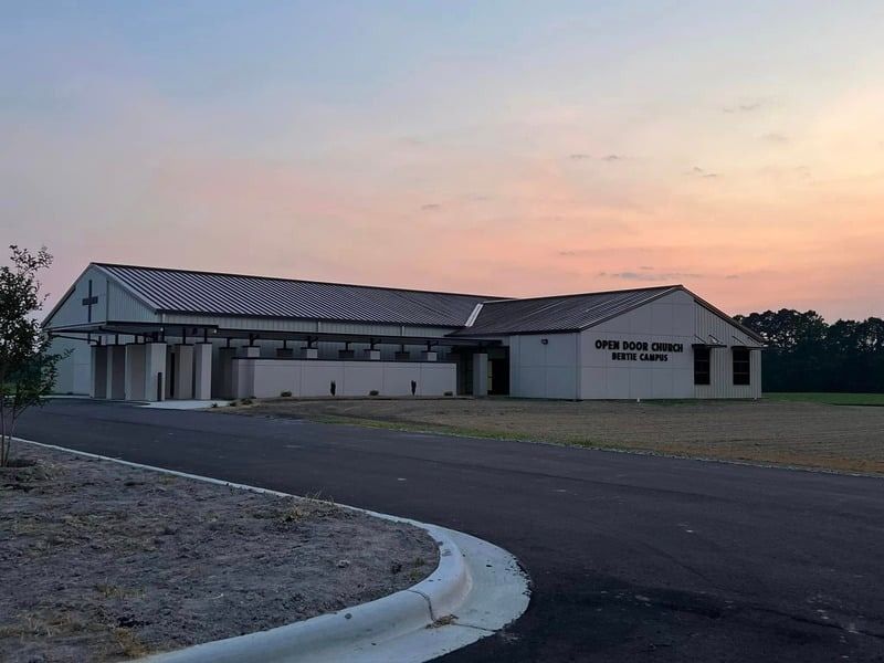 Single-story building at dusk with a paved driveway and sunset sky