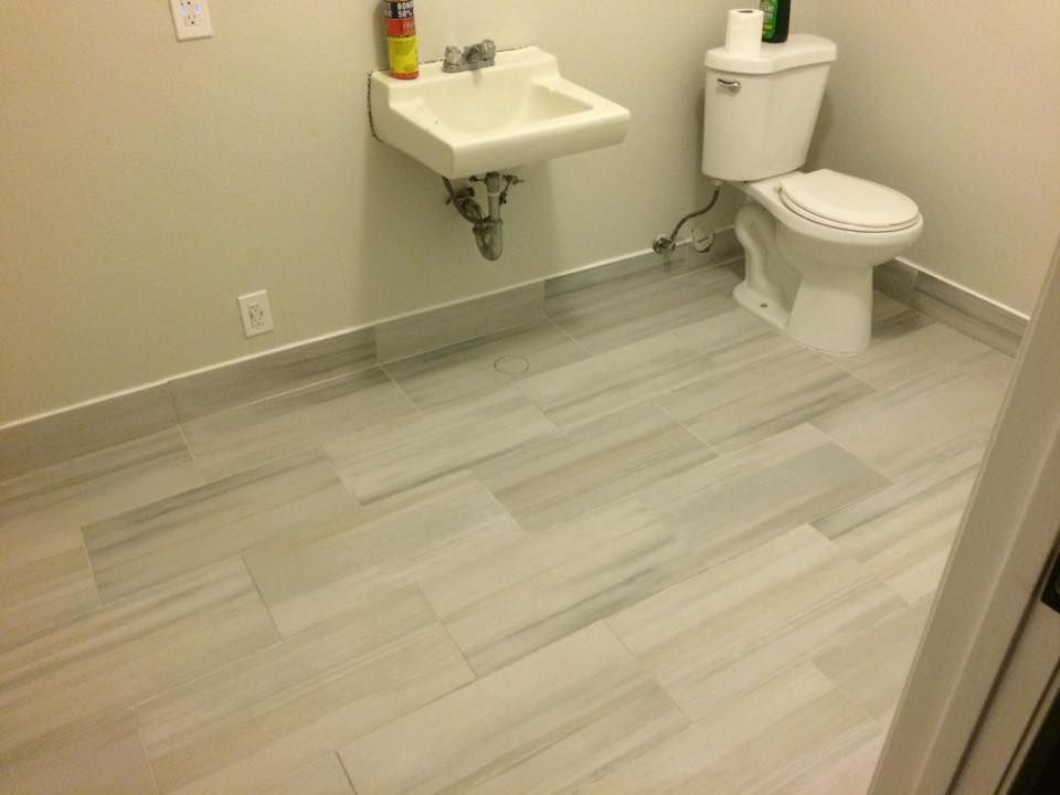 A bathroom with a toilet , sink and tiled floor.