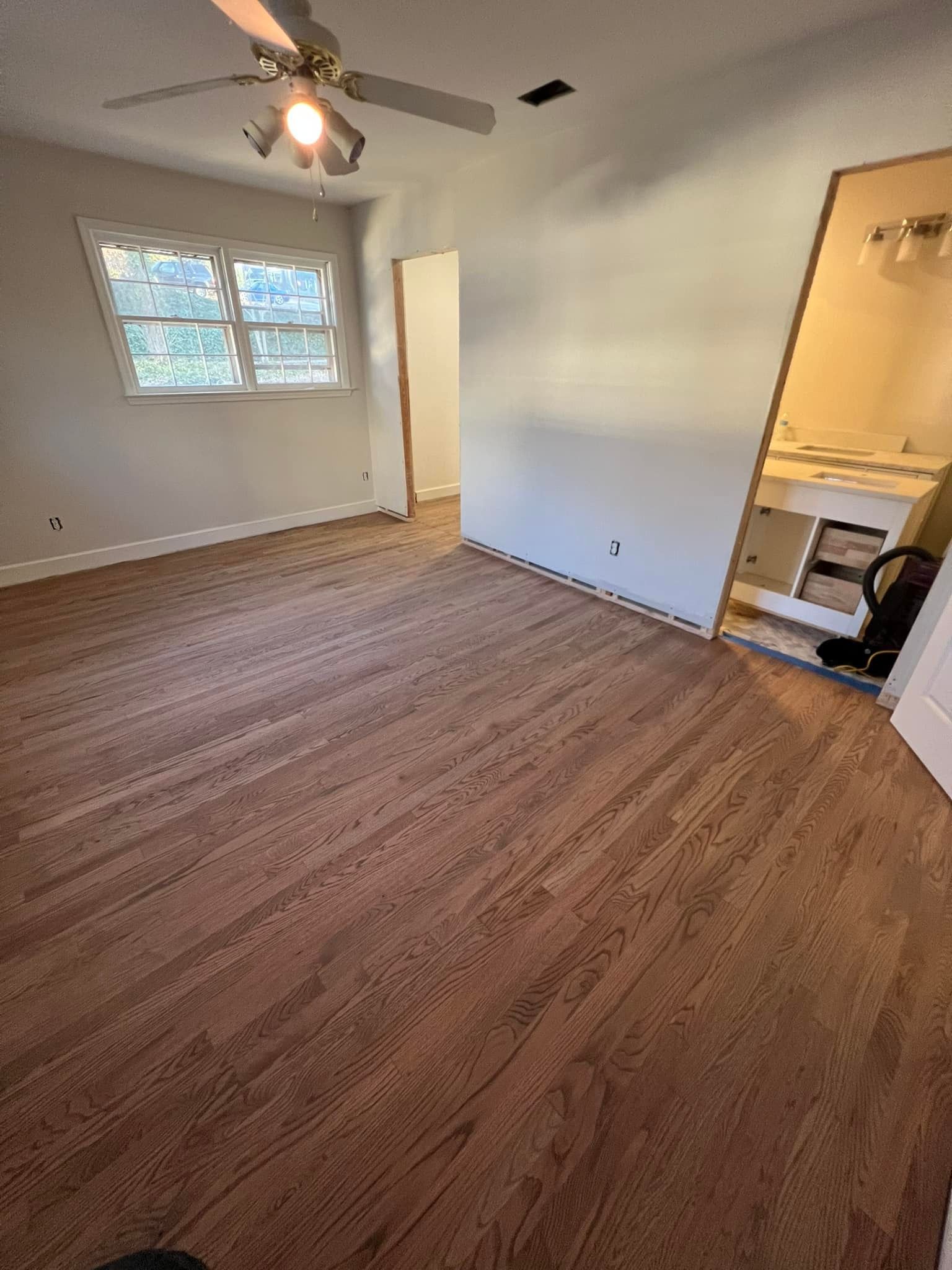 A bedroom with hardwood floors and a ceiling fan.