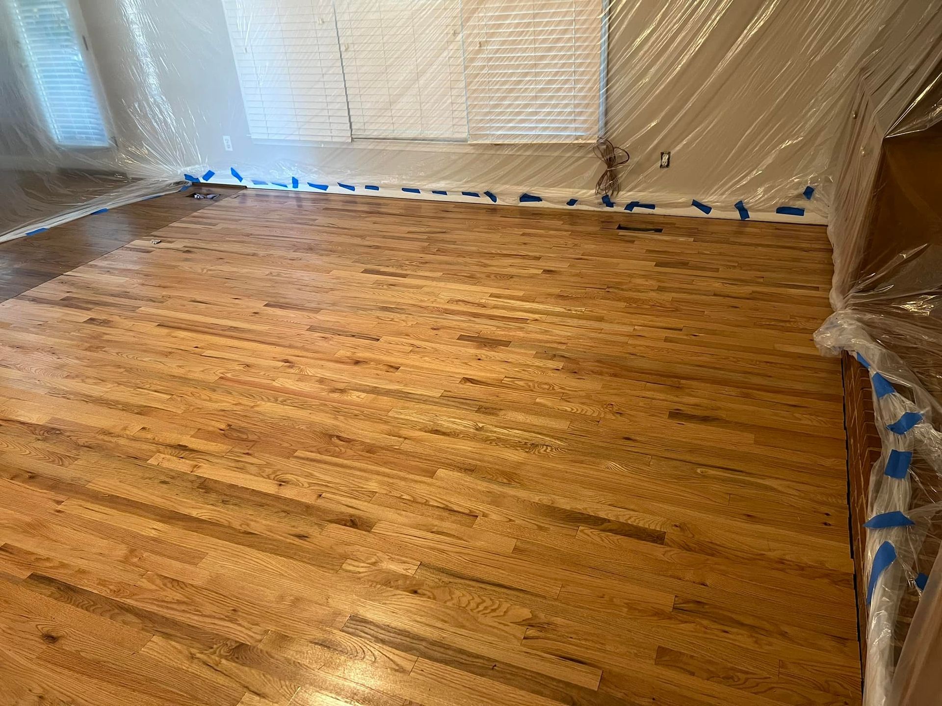 A wooden floor is being painted in a living room.
