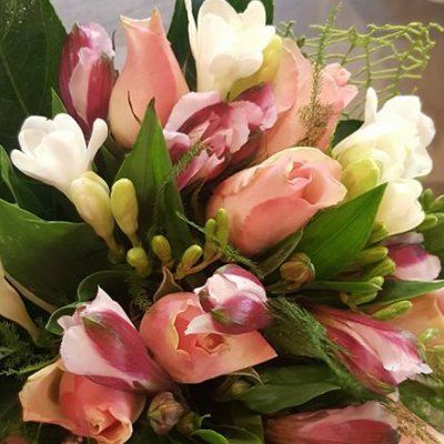 Un primo piano di un bouquet di fiori rosa e bianchi con foglie verdi.