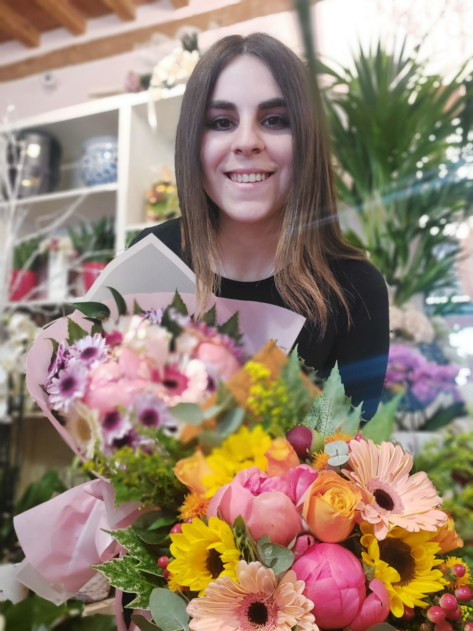 Una donna tiene in mano un mazzo di fiori in un negozio di fiori.