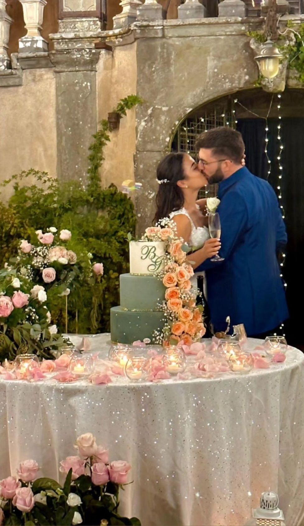 Una sposa e uno sposo si baciano davanti a una torta nuziale.