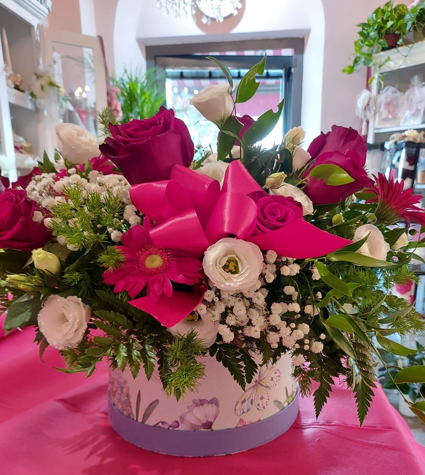 Una scatola piena di fiori con un fiocco rosa
