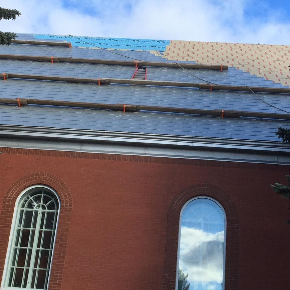 Un bâtiment en briques rouges, avec des fenêtres cintrées et un toit en ardoise, est en cours de réparation, des échafaudages étant en place.