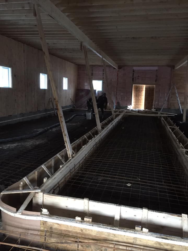 Chantier de construction intérieur présentant une structure de coffrage en bois pour une dalle en béton armée d'un treillis métallique.