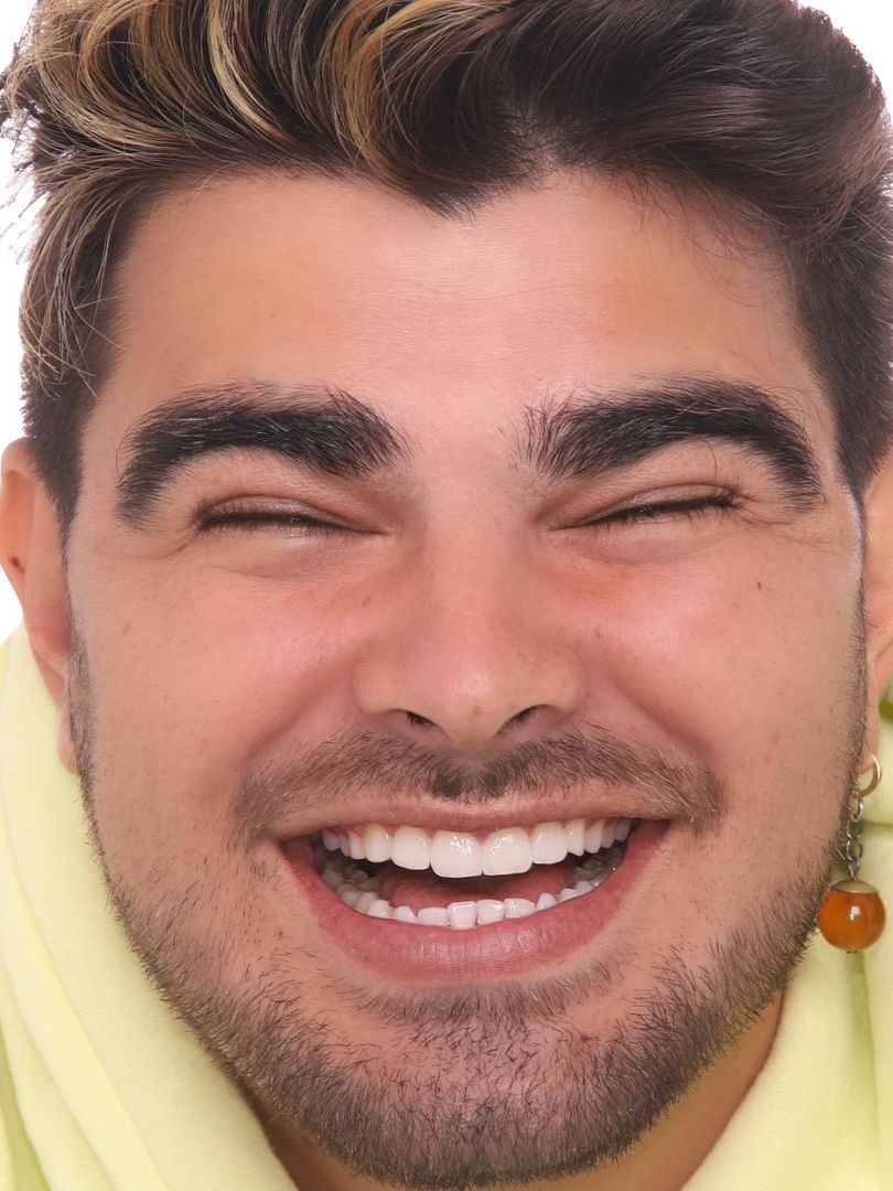 A man with a beard is smiling with his eyes closed.