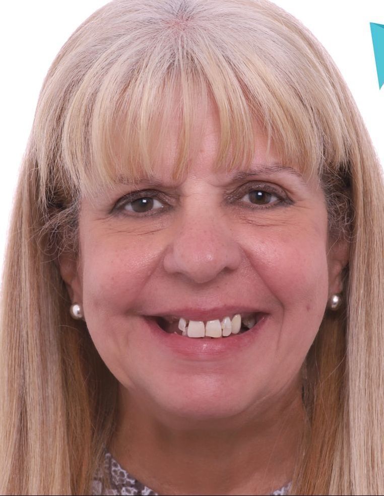 A woman with blonde hair and earrings is smiling for the camera.