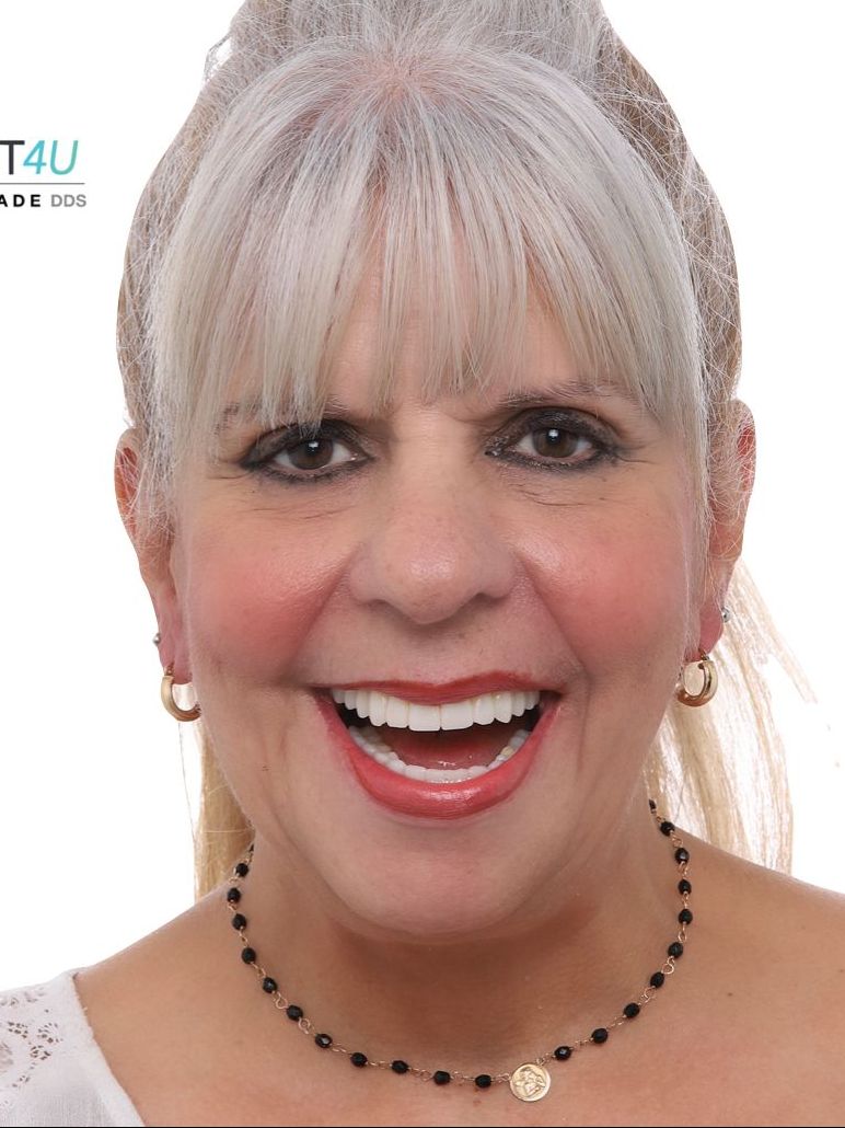 A woman wearing a necklace and earrings is smiling for the camera.