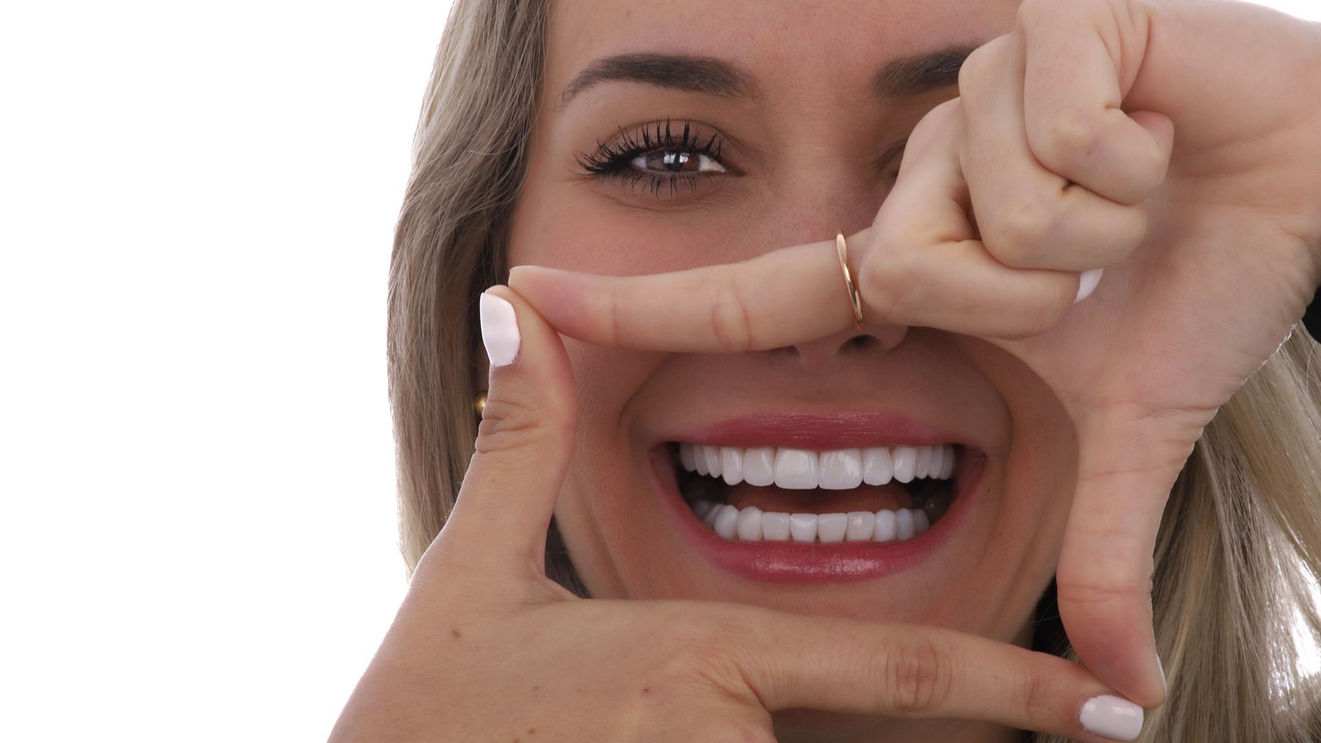 A woman is smiling and making a frame with her fingers.