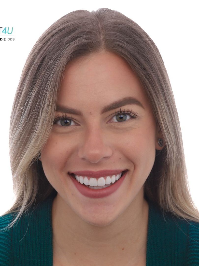 A woman is smiling and wearing a green sweater