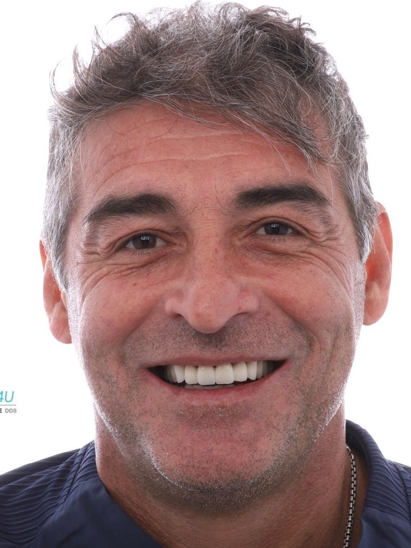 A man with gray hair and a beard is smiling for the camera.