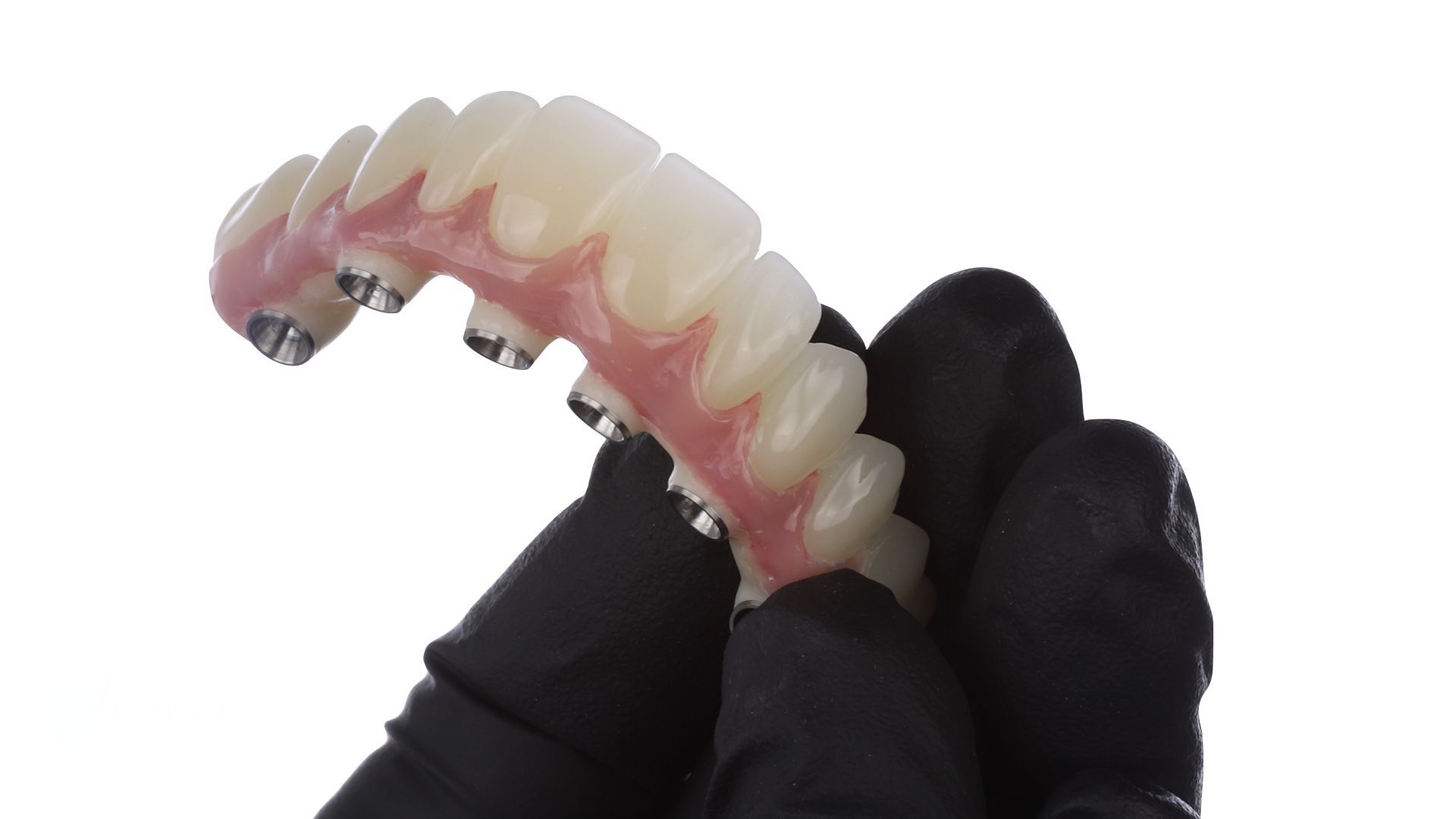 A person wearing black gloves is holding a denture in their hand.