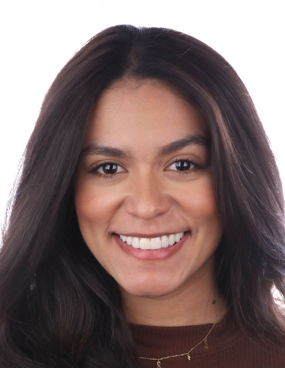 A woman with long dark hair is smiling for the camera