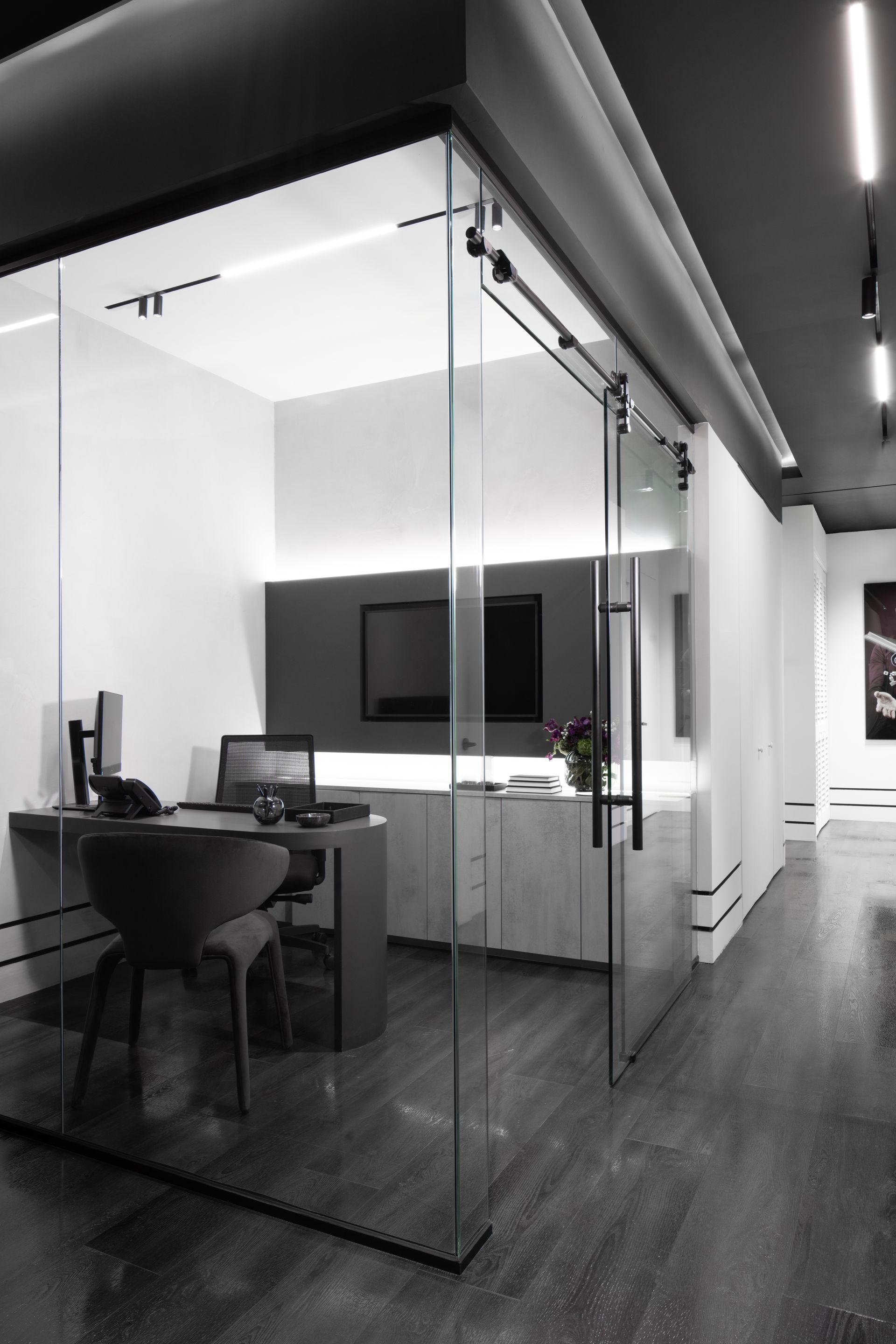 A black and white photo of an office with a glass wall