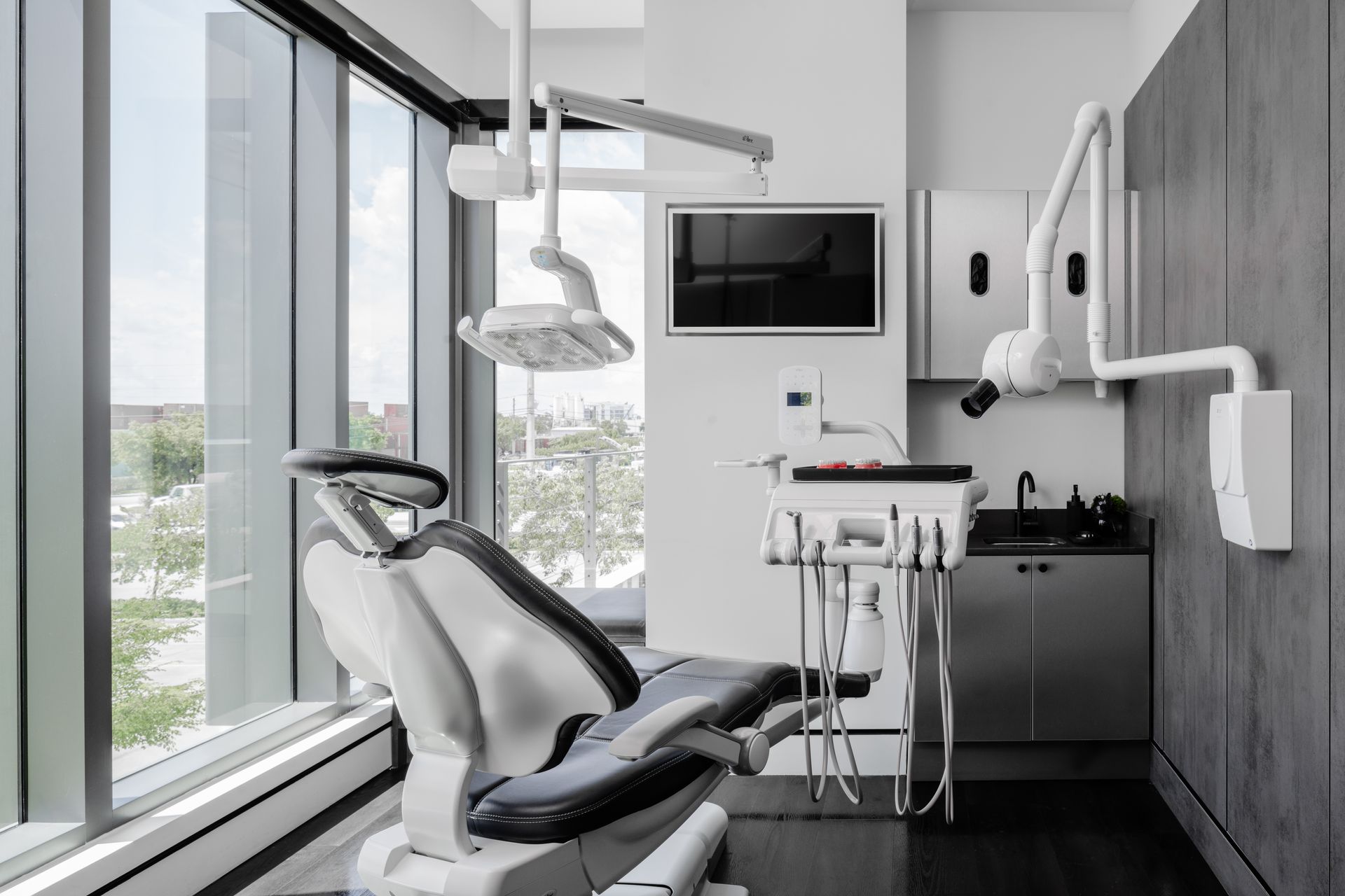 A dental office with a dental chair , sink , and television.