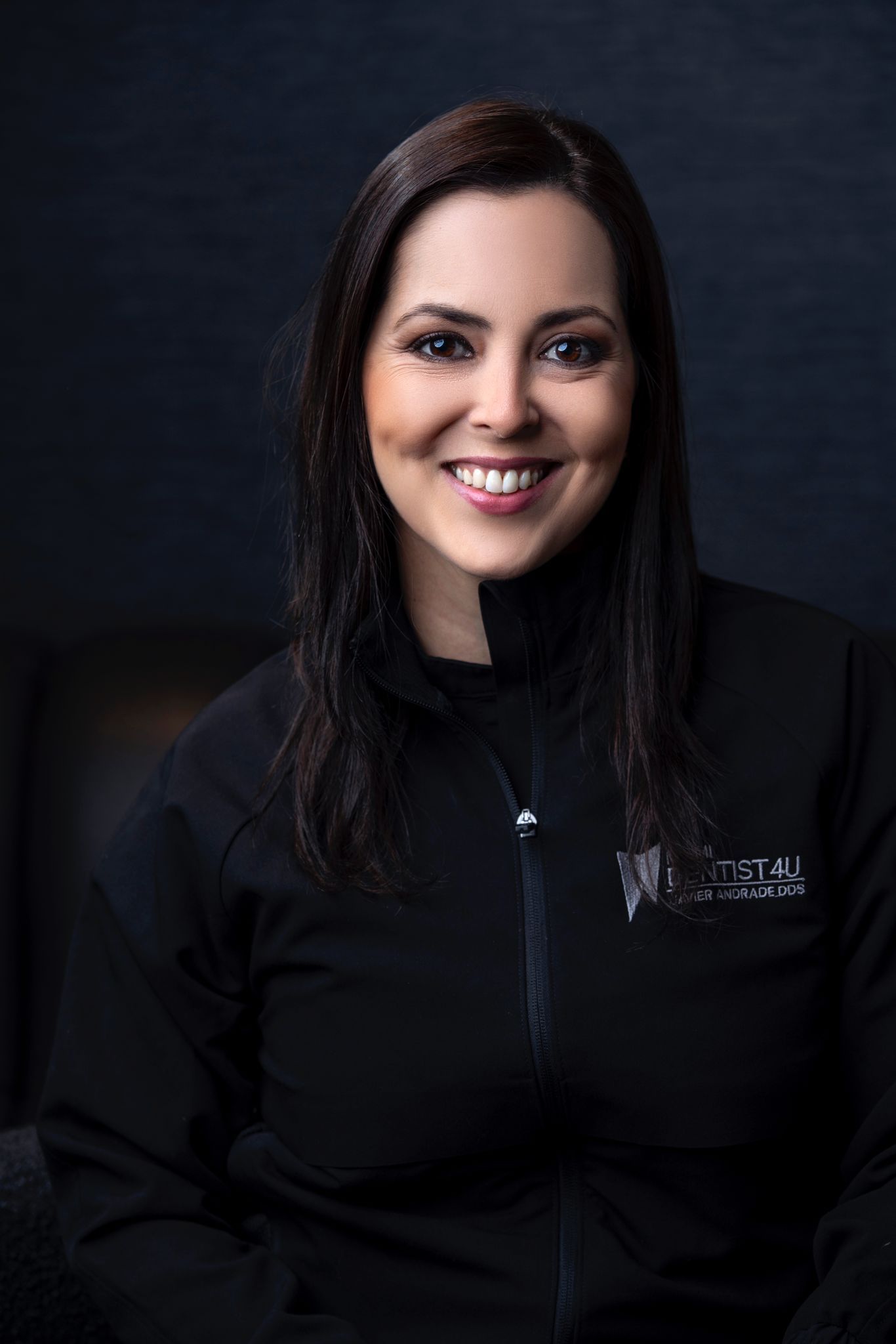 A woman in a black jacket is smiling for the camera.