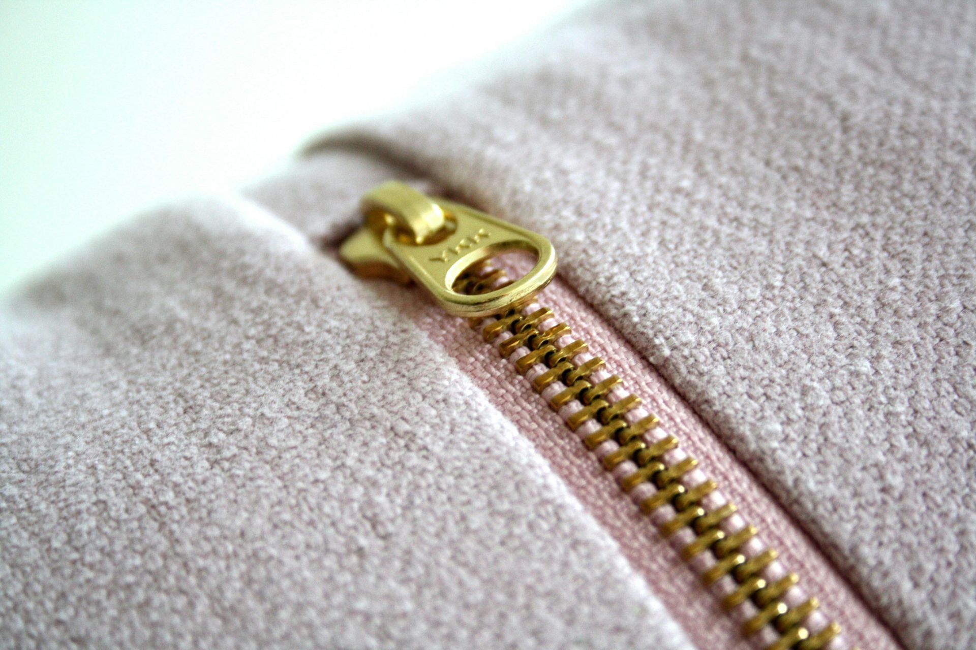 A close up of a pink zipper on a white surface.