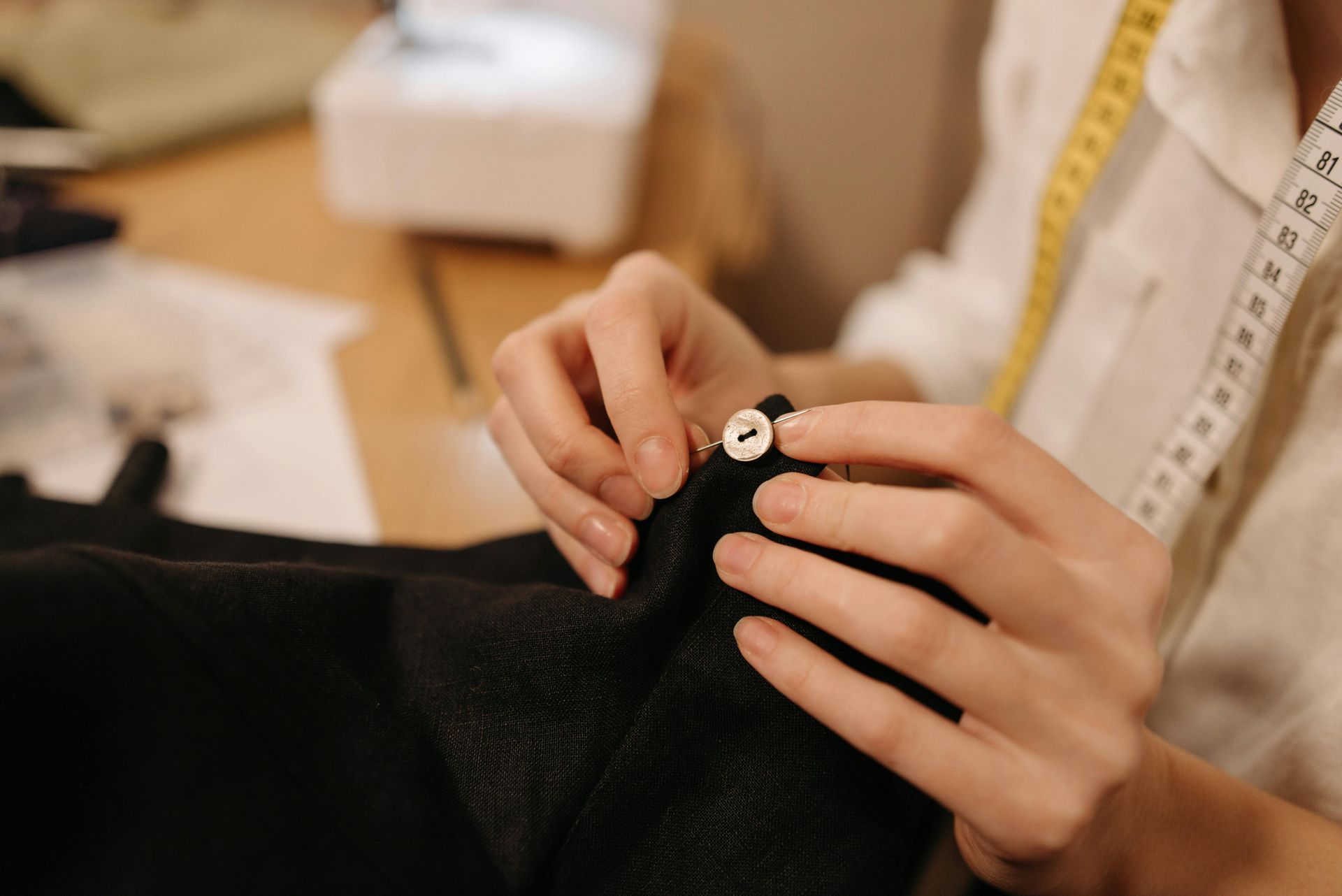 A woman is sewing a piece of fabric with a sewing machine.
