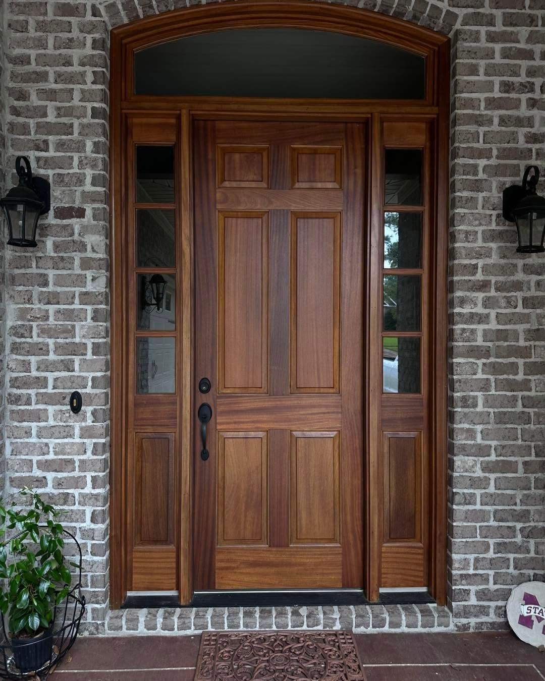 Wooden front door with sidelights set in a brick exterior wall