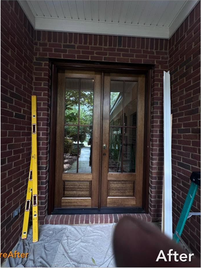 Wooden door with glass panel and decorative elements, resting on sawhorses.