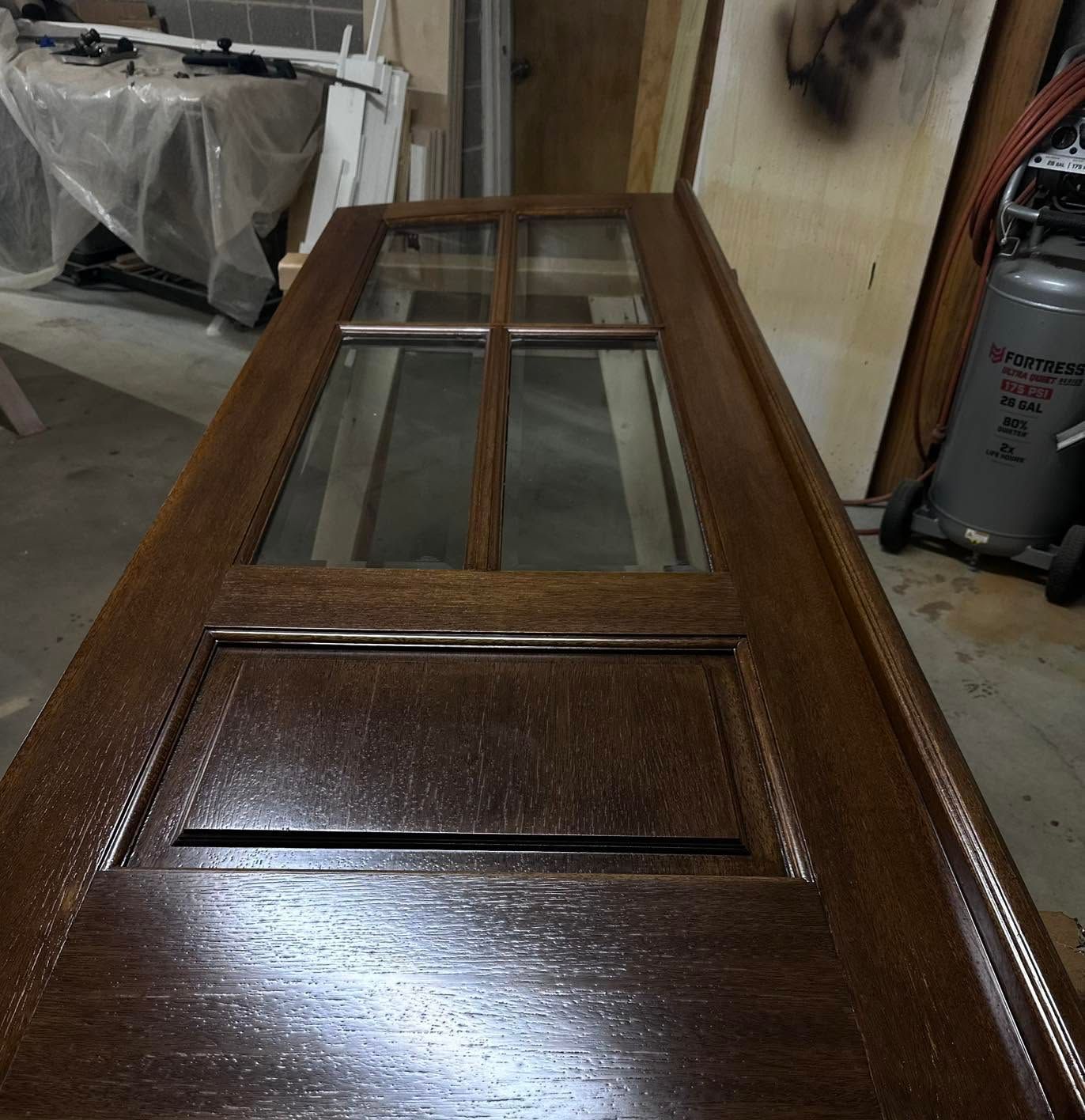 Wooden door with glass panes and a raised panel, shown in a workshop or garage.