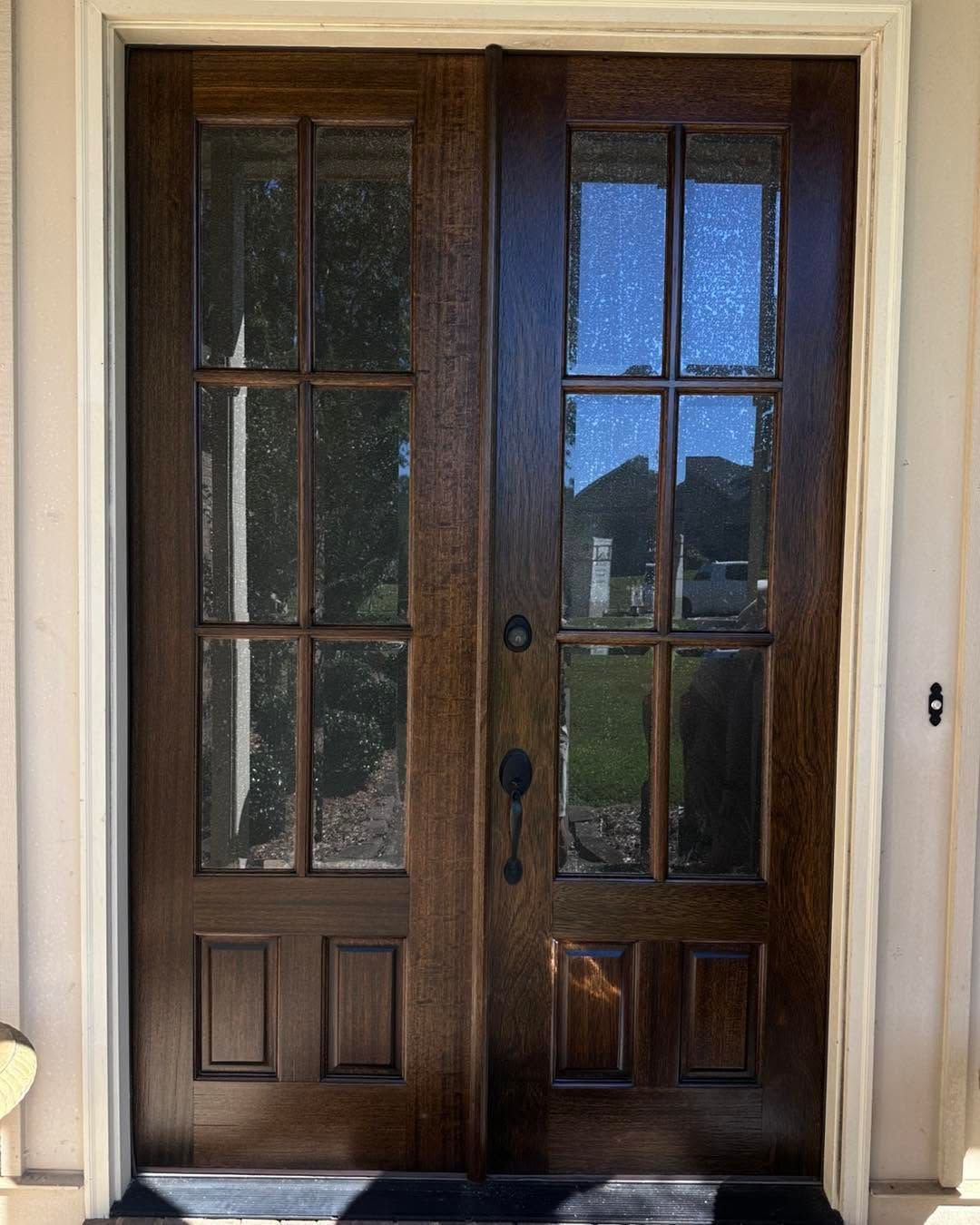 Wooden double front doors with glass panes and a view outside