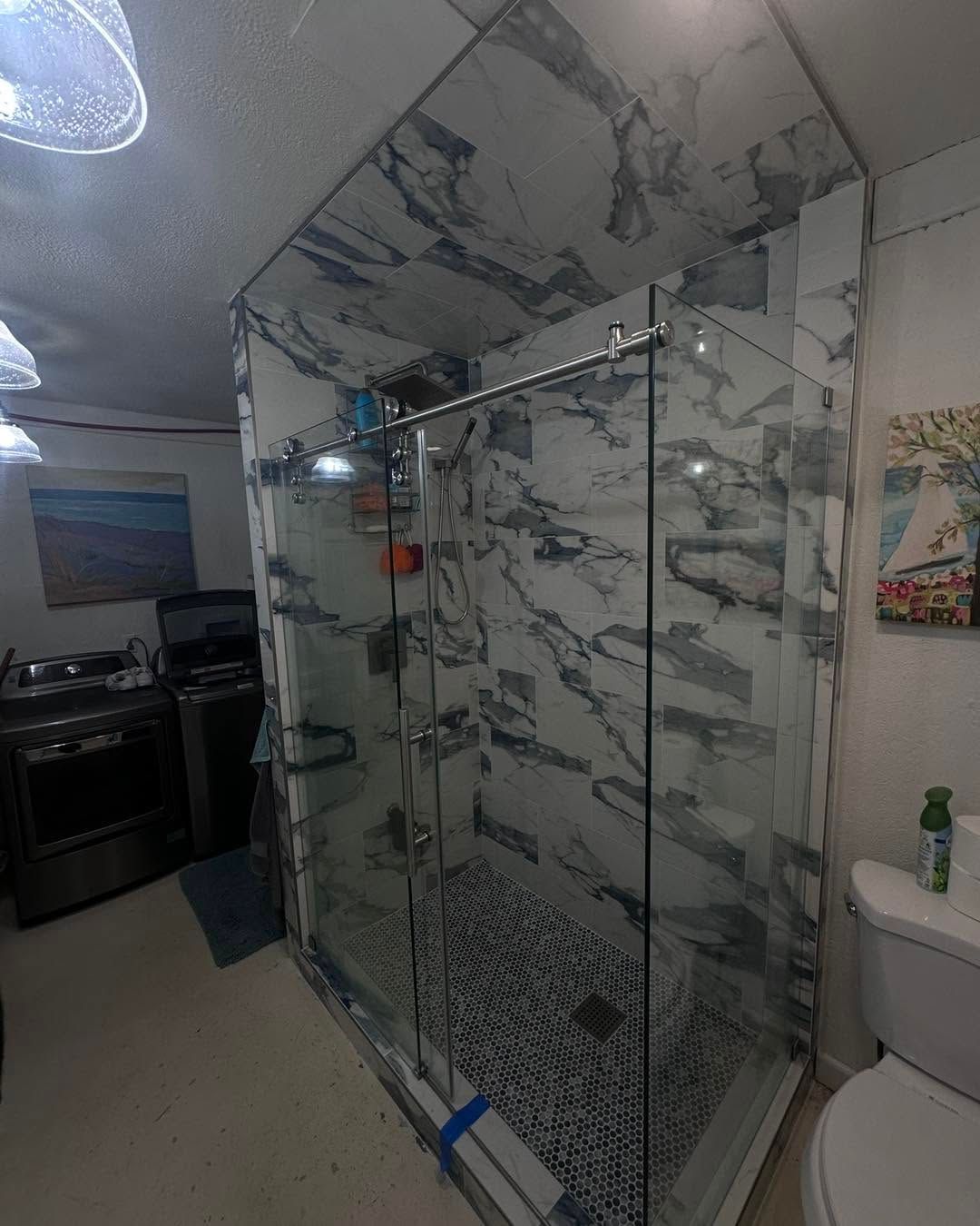 Bathroom with marble-look shower enclosure, glass door, and toilet beside it