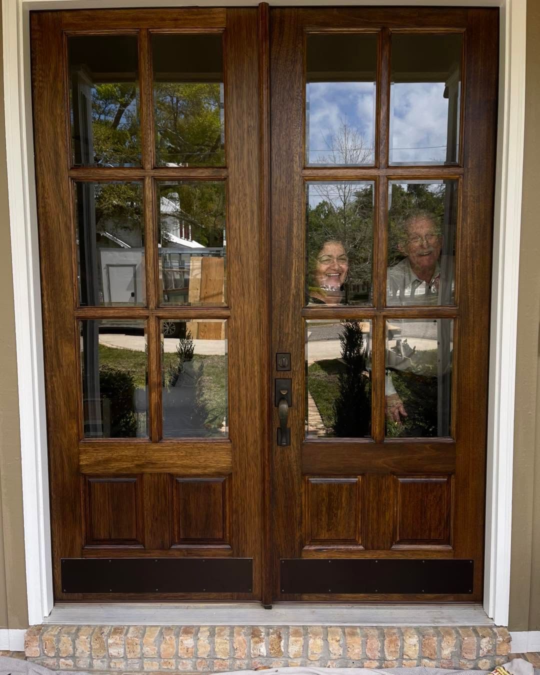 Wooden double front doors with glass panes and a decorative brick threshold