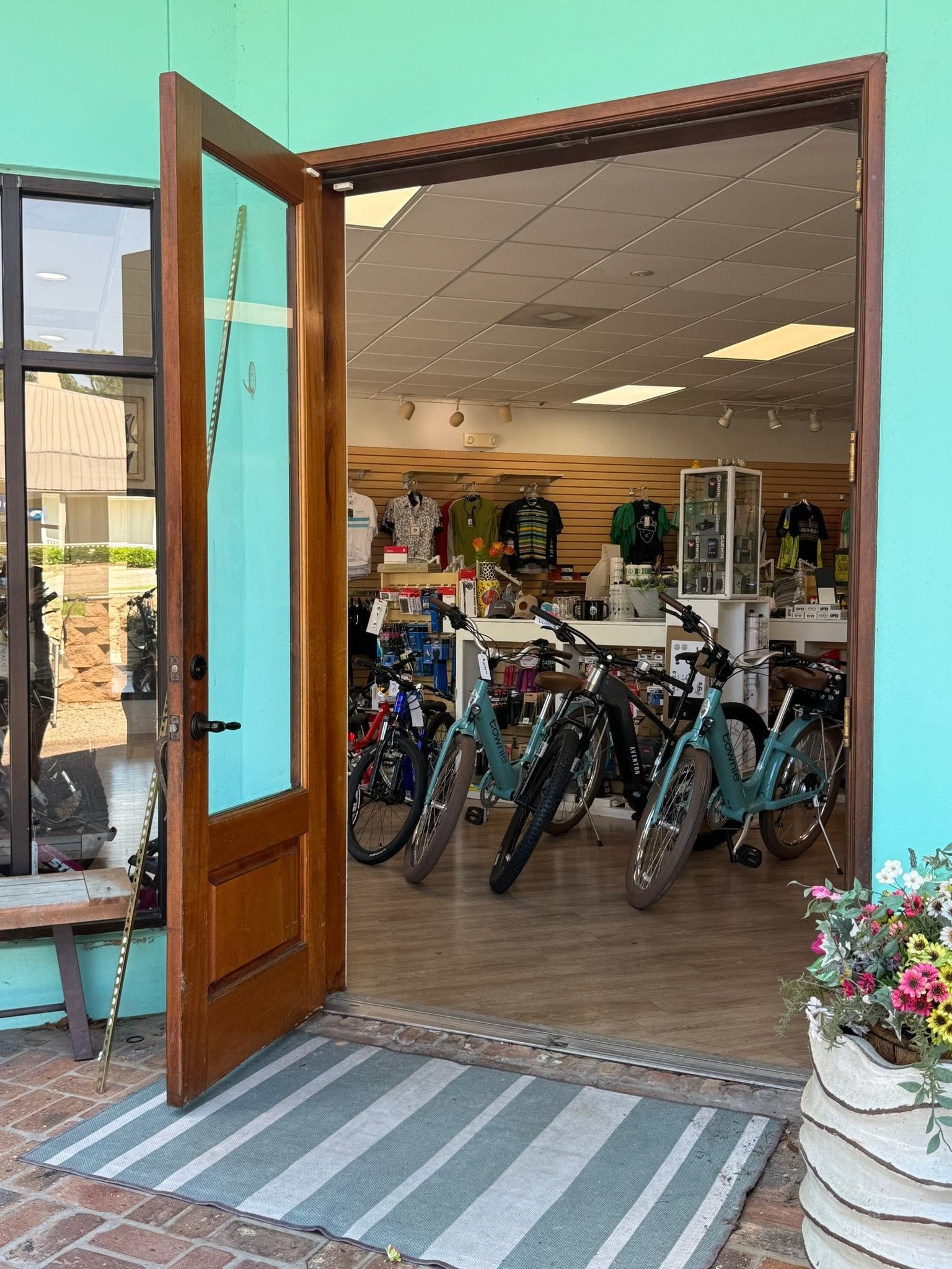 Open shop doorway with several bicycles displayed inside and a striped mat at the entrance