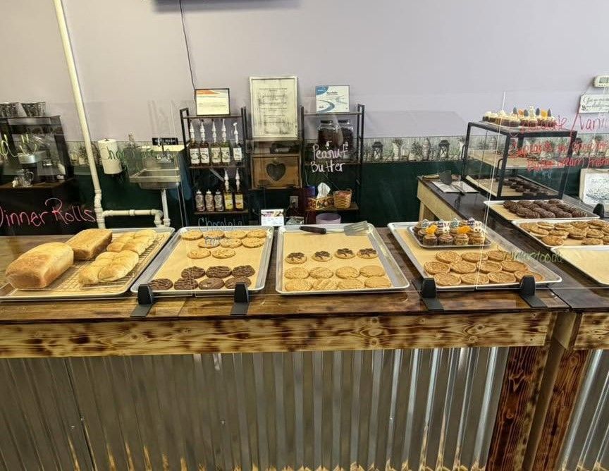 Bakery counter with assorted pastries on trays and bread loaves on a rustic display table