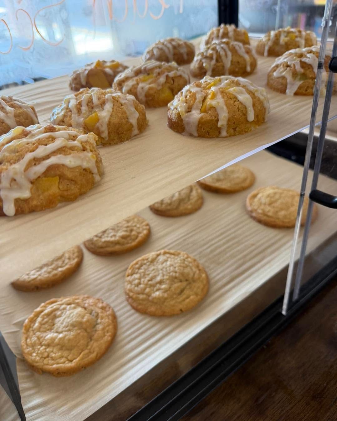 Tray of glazed pastries and plain cookies displayed behind a glass case.