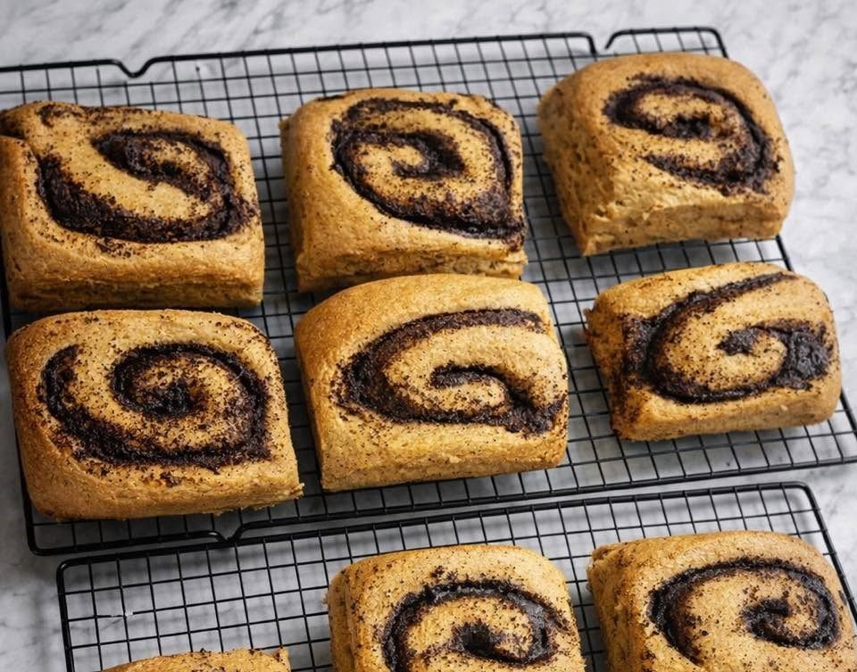 Nine cinnamon rolls cooling on a wire rack, golden brown with dark cinnamon swirls.