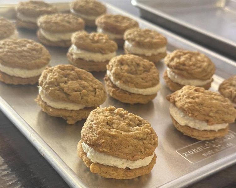 Tray of oatmeal sandwich cookies with cream filling on a bakery display counter