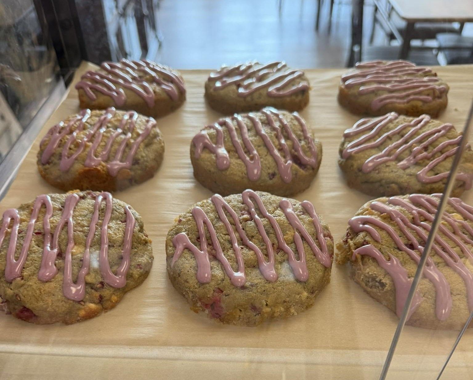 Iced pastries on a display tray behind a glass case