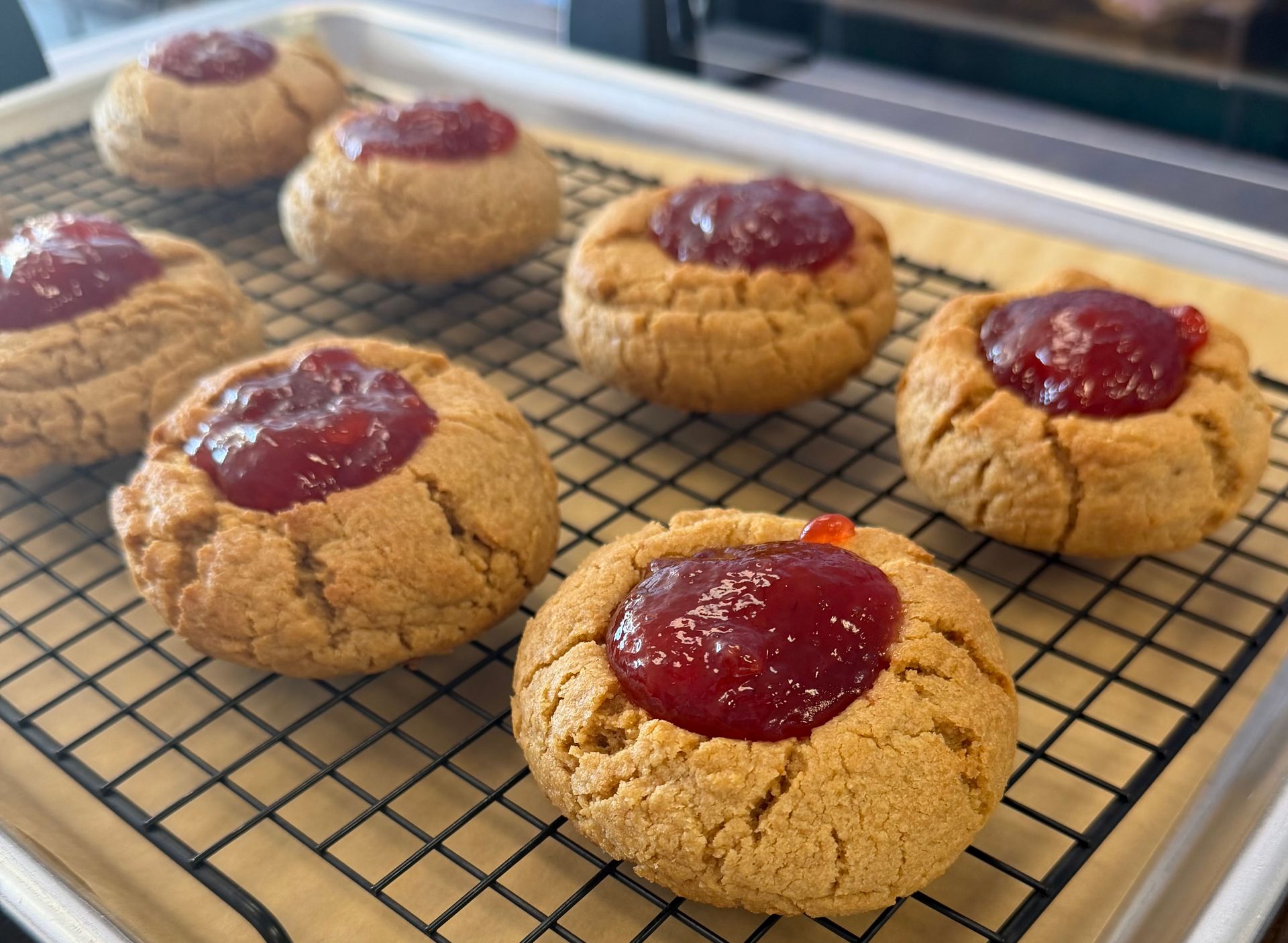 Fresh jam thumbprint cookies cooling on a wire rack