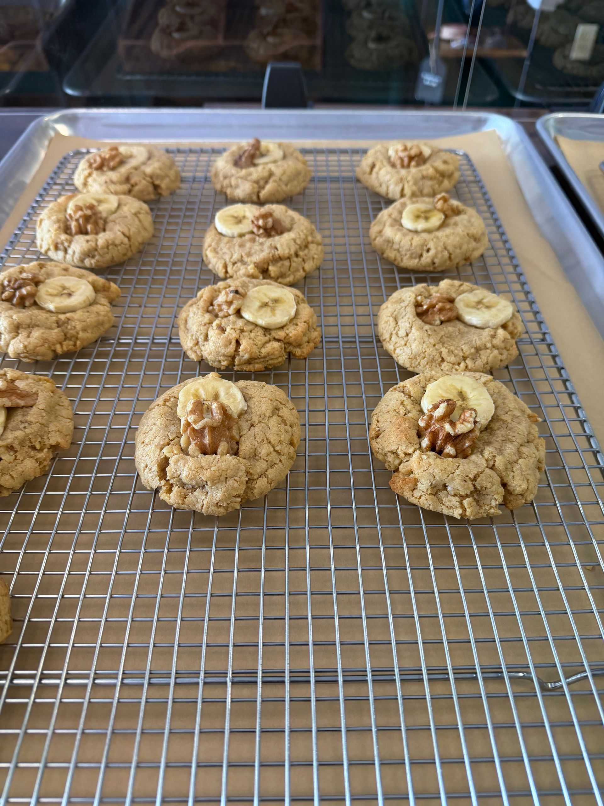 Tray of baked cookies cooling on a wire rack in a kitchen display case.