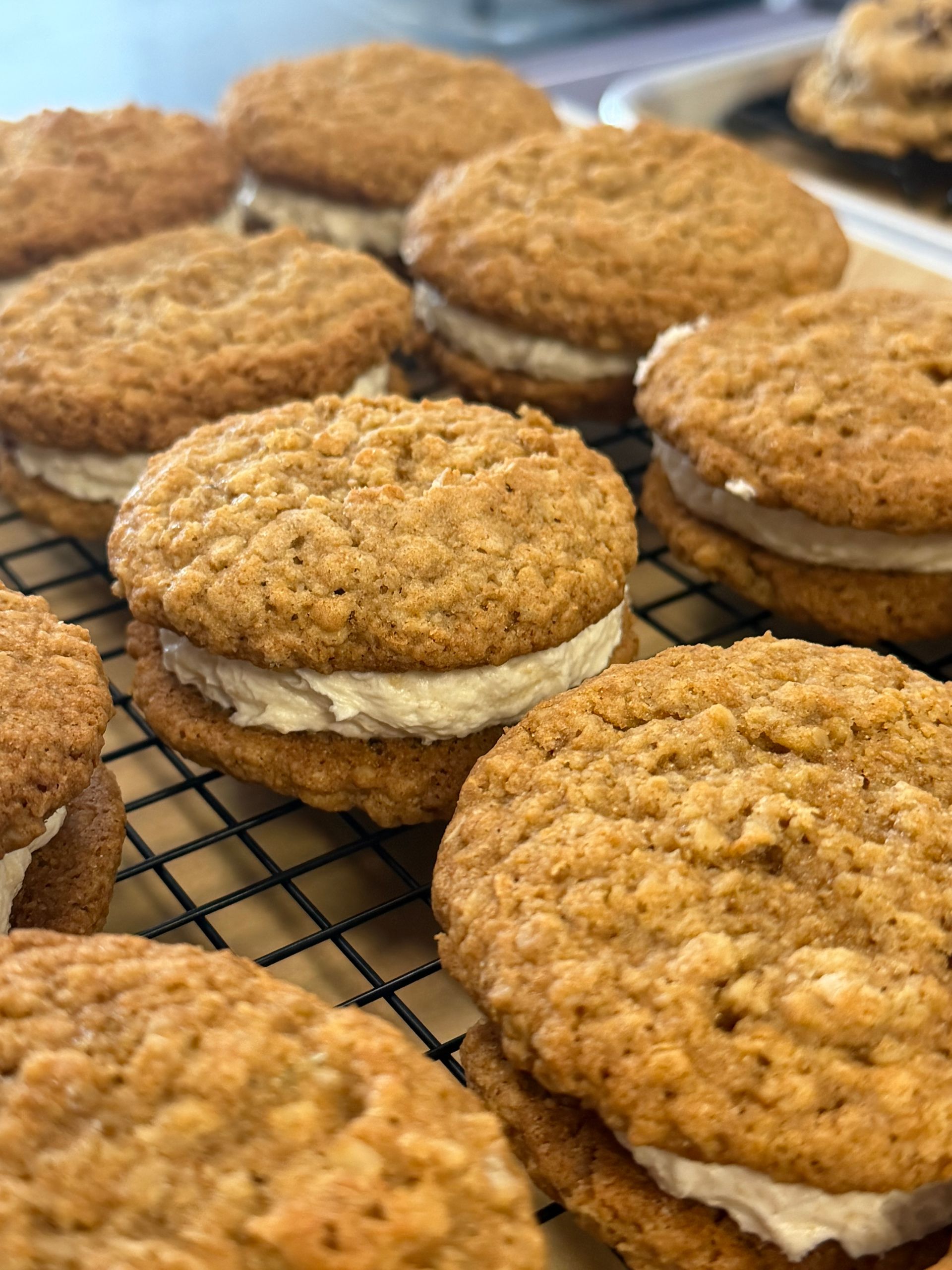Oatmeal cream cookies cooling on a wire rack, with a golden-brown, textured surface.