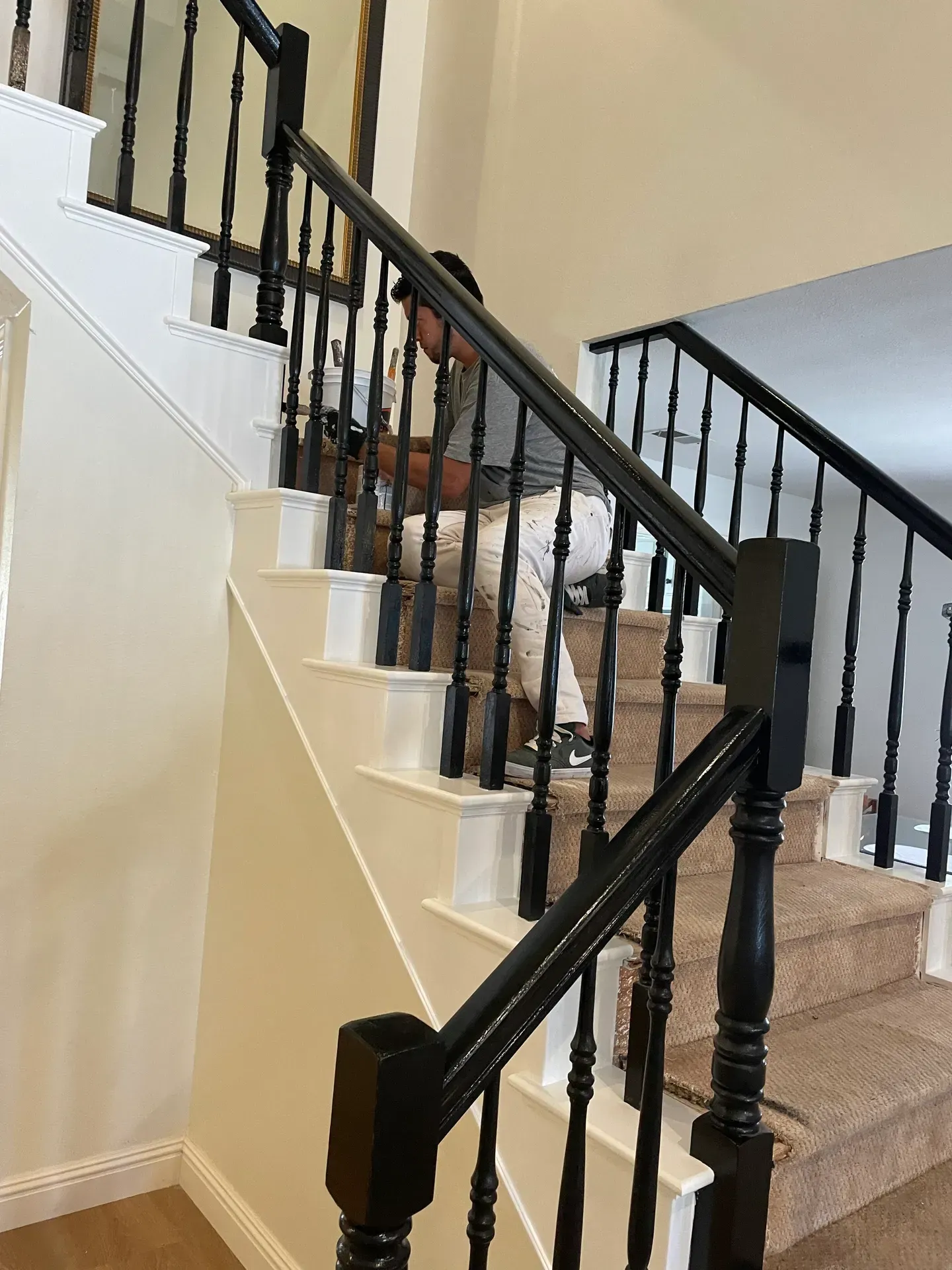 A man is sitting on a set of stairs with a black railing.